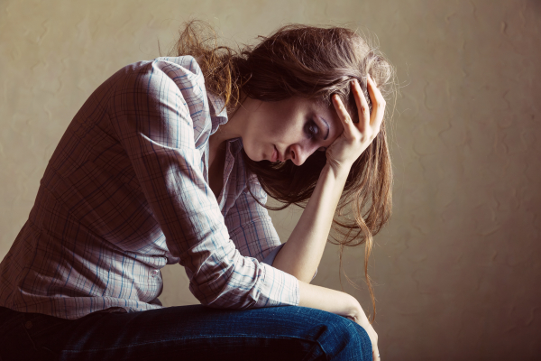 Young sad girl sitting alone in an empty room